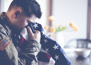 American soldier mourning praying with American flag in his hands