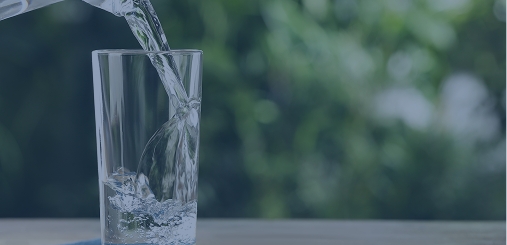 Pouring water into glass of water on wooden table outdoors