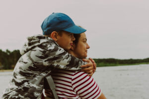 Lakeside family affection son embracing mother on camping getaway