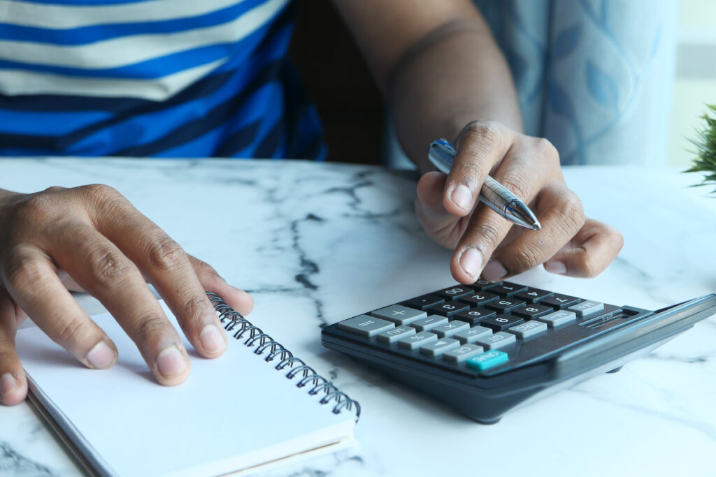 Person hand using calculator and writing on notebook